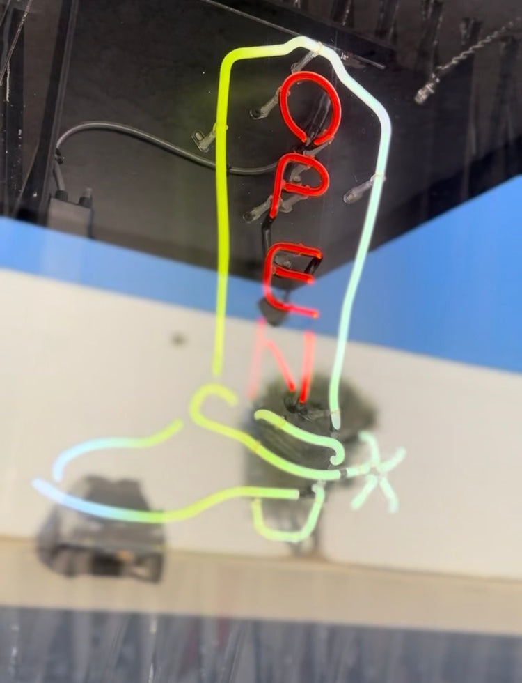 Neon cowboy boot OPEN sign in the shop window